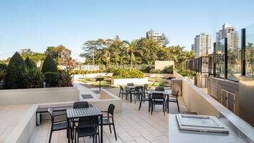 Relax on the outdoor terrace with comfortable seating and lush greenery, offering a view of the city.