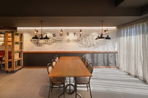 A dining area with a long wooden table, chairs, and a wall with a skeleton design and the word "GUSTI" above it. - The Sebel Twin Towns Coolangatta (Tweed Heads)