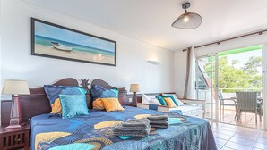 Een slaapkamer met een groot bed, een schilderij van een strand en uitzicht op de omgeving.