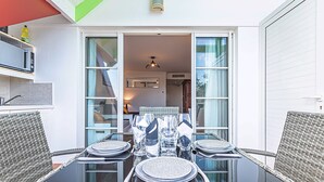 An outdoor dining area with wicker chairs and a glass table set for four. - Studio Karuker’As - Aouara 1326 (Sainte-Anne)