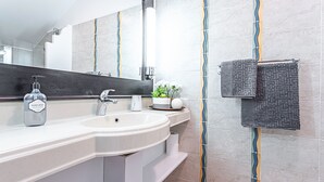 A modern bathroom with a white sink, a large mirror, and a towel rack with a patterned towel. - Studio Karuker’As - Aouara 1326 (Sainte-Anne)