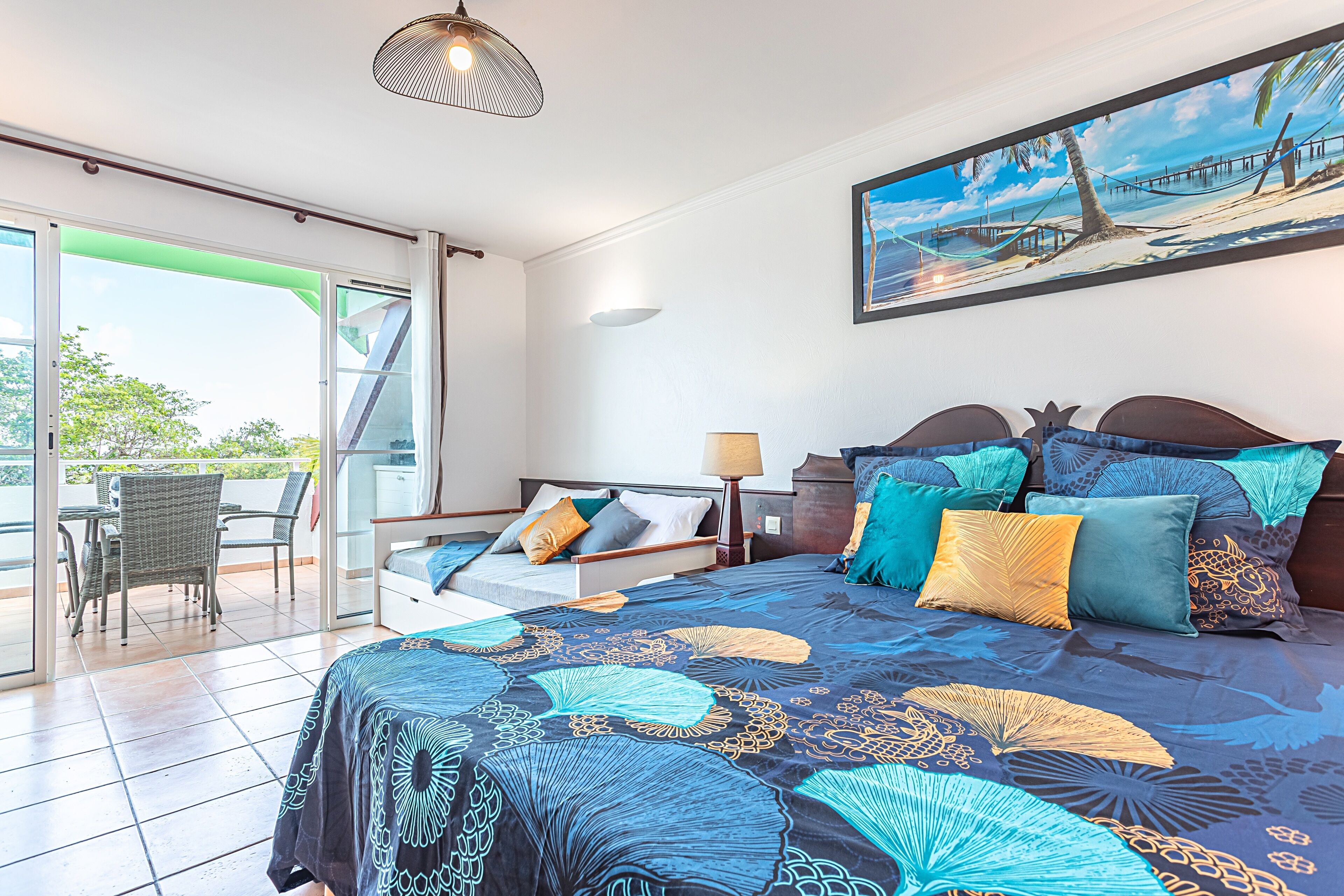 Ein Schlafzimmer mit Bett, Stuhl, Tisch und Blick ins Freie.