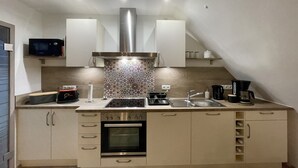 A modern kitchen with a built-in oven, a microwave, a coffee maker, and a sink. - Beautiful vacation apartment at the pulse of the Green Hell (Kelberg)