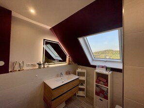Un baño moderno con tragaluz, un espejo grande y un mueble de tocador de madera.