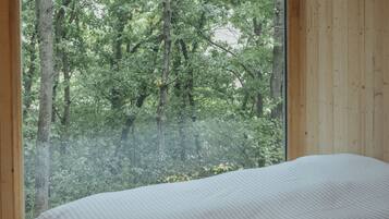 Un dormitorio con un ventanal que ofrece vistas a un bosque.