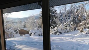 A view from inside a building looking out at a snowy landscape with trees and a wooden structure. - Maison Familiale "les 3 Roches" (Xonrupt-Longemer)