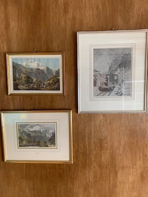 Drei gerahmte Landschaftsbilder an einer Holzwand.