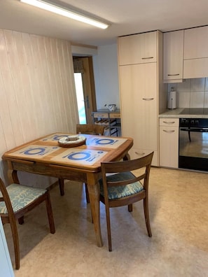 A compact kitchen with a dining table and chairs, a built-in oven, and a small countertop.