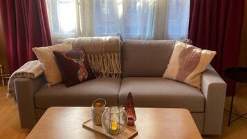 Una sala de estar con sofá, una mesa de centro y una ventana con cortinas.