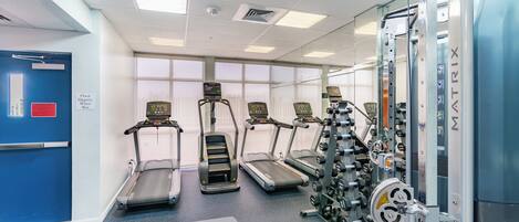 A gym with treadmills, weight machines, and benches.
