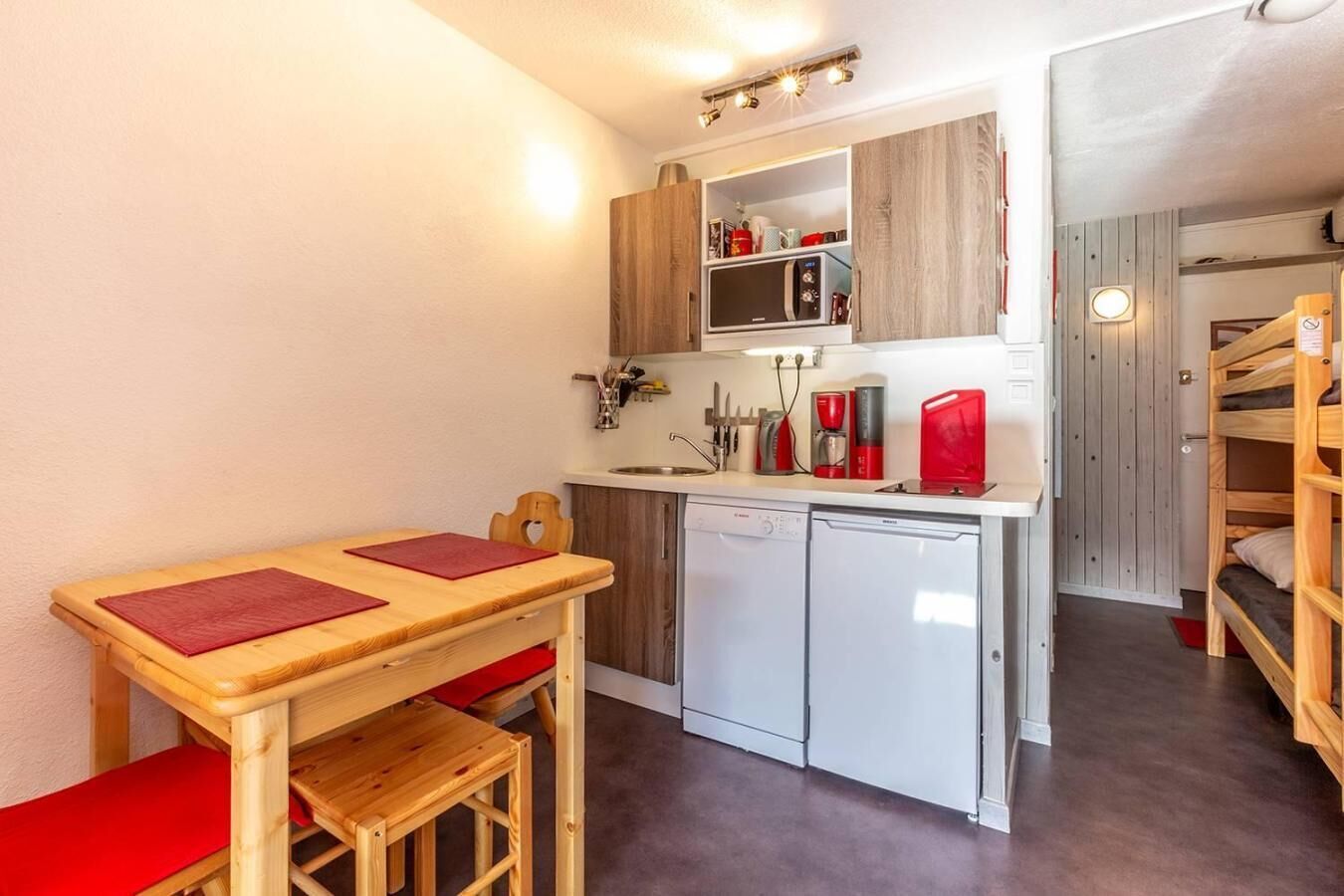 A compact kitchen with a wooden table and chairs, a dishwasher, and a microwave.