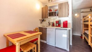 Eine kleine Küche mit einem Holztisch und Stühlen, einem Geschirrspüler und einer Mikrowelle.