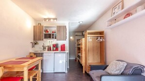 Ein kompakter Wohnraum mit Küchenzeile, Essbereich und Sitzecke mit Sofa und kleinem Tisch.