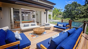 Un espace de vie extérieur moderne avec une piscine, des meubles bleus et blancs et une terrasse en bois.