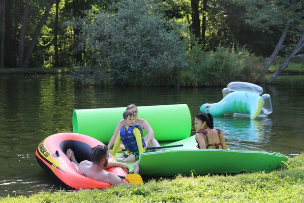 A group of people on inflatable rafts in a calm body of water surrounded by greenery.