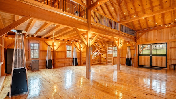 Een ruim houten interieur met hoge plafonds, grote ramen en een centrale trap.
