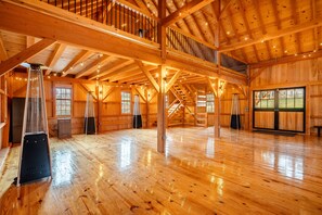 A spacious wooden interior with high ceilings, large windows, and a central staircase.