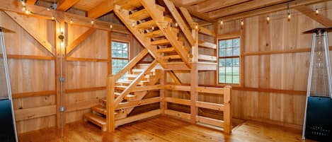 Un interior de madera con una escalera central, ventanas amplias y un ventilador de techo.