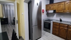 A kitchen with wooden cabinets, a stainless steel refrigerator, a built-in oven, and a granite countertop.