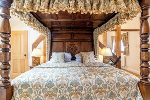 A four-poster bed with a floral bedspread, wooden headboard, and two bedside lamps. - Townhouse Ludlow (Ludlow)