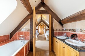 A bathroom with two sinks, wooden beams, and a hallway leading to a bedroom. - Townhouse Ludlow (Ludlow)