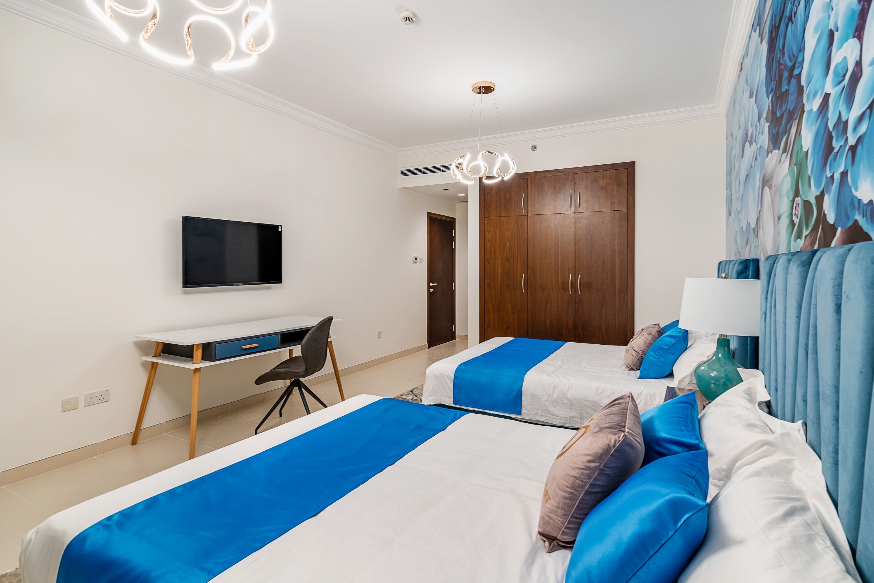 Ein Hotelzimmer mit zwei Betten, einem Schreibtisch, einem Fernseher und einem Kleiderschrank.