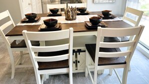 A dining area with a round table, white chairs, and black bowls on square plates. - Modern Vibe, 5 Beds, 6 pools, Great Location (Lake Ozark)