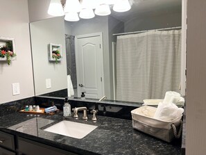 A bathroom with a large mirror, a sink, a towel rack, and a shower curtain.