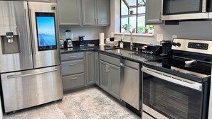 A modern kitchen with stainless steel appliances, grey cabinetry, and a built-in oven. - Modern Vibe, 5 Beds, 6 pools, Great Location (Lake Ozark)
