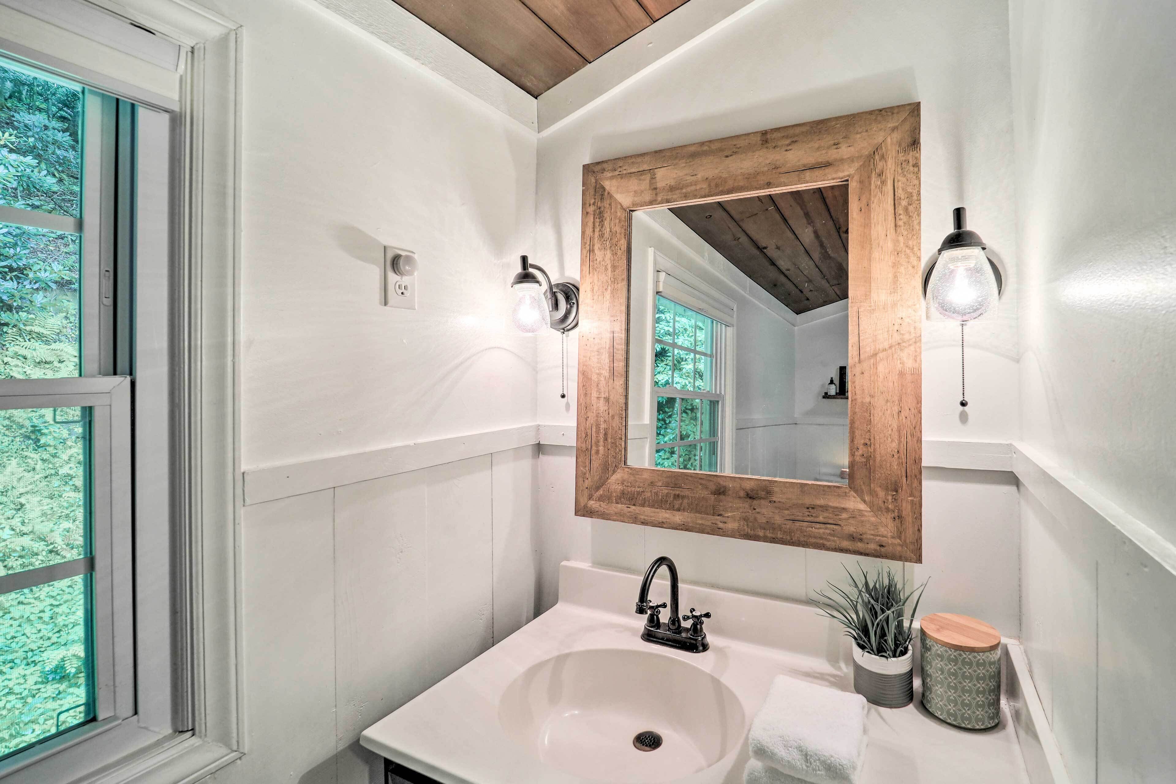 Une salle de bain avec un lavabo blanc, un miroir encadré en bois et deux appliques murales.