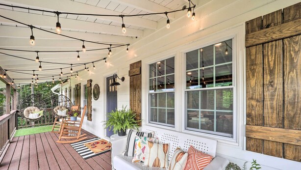 A covered porch with a wooden bench, string lights, and potted plants. - Riverfront Sugar Grove Home: Hot Tub & Views! (Sugar Grove)