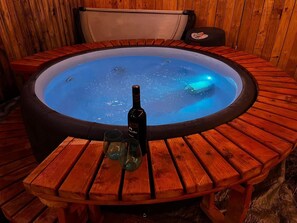 A hot tub with a bottle and glasses on a wooden table. - Cozy Bungalow, close to the lake. (Graford)