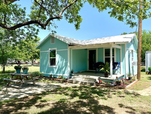 A small, single-story house with a porch, a small garden, and a picnic table. - Cozy Bungalow, close to the lake. (Graford)
