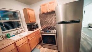 A modern kitchen with wooden cabinets, a stainless steel refrigerator, a microwave, and an oven. - Cozy Bungalow, close to the lake.  (Graford)