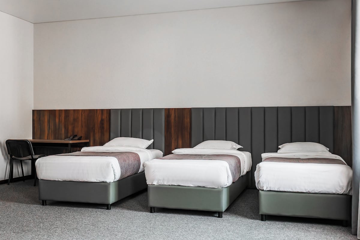 Una habitación de hotel con cuatro camas, un escritorio y una silla.