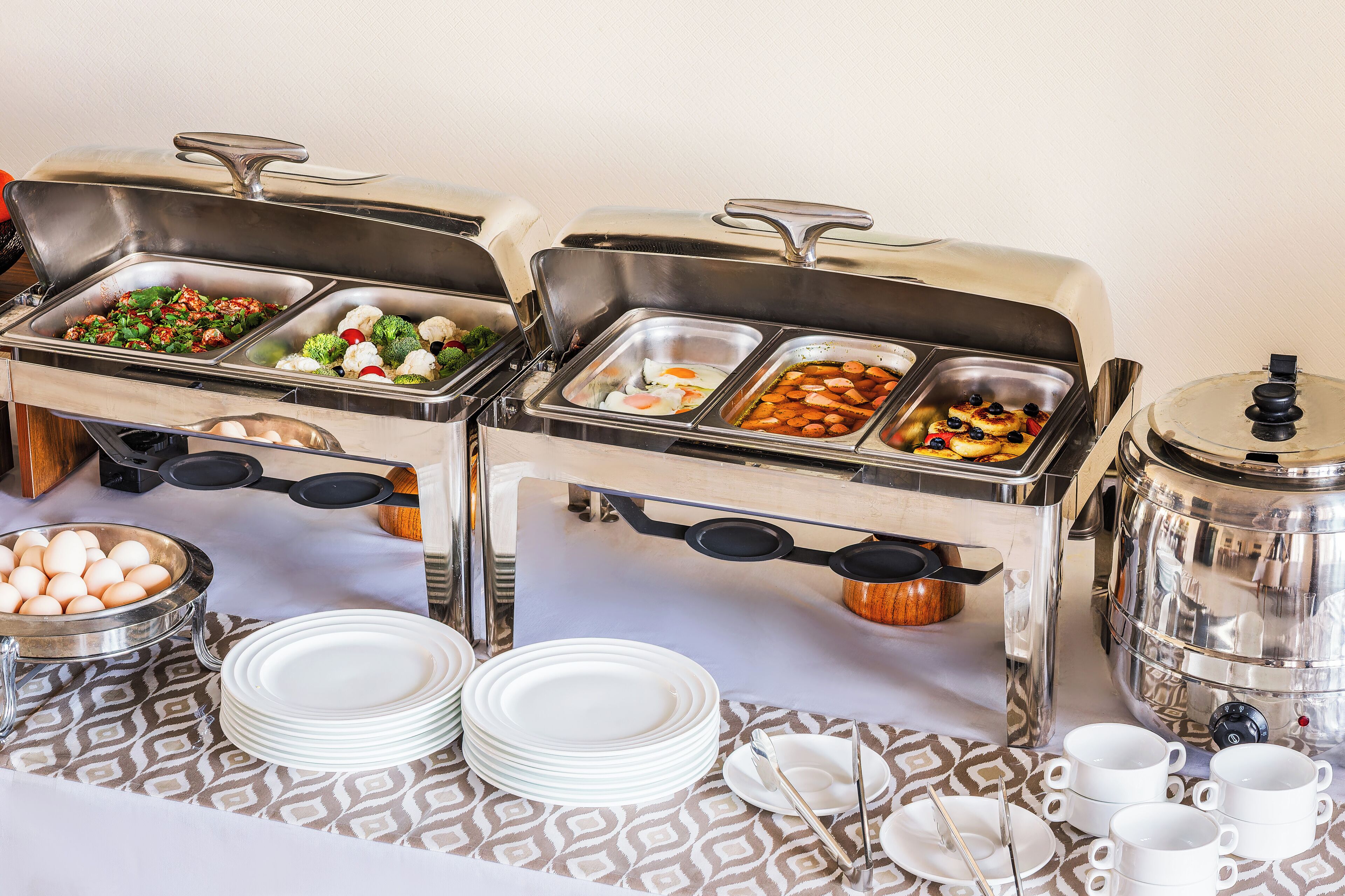 Een buffetopstelling met verschillende food stations, waaronder eieren, groenten en vlees.