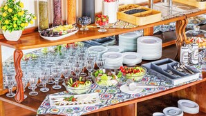 A buffet table with various food items, glassware, and salad bowls. - Grand Nur (Tashkent)