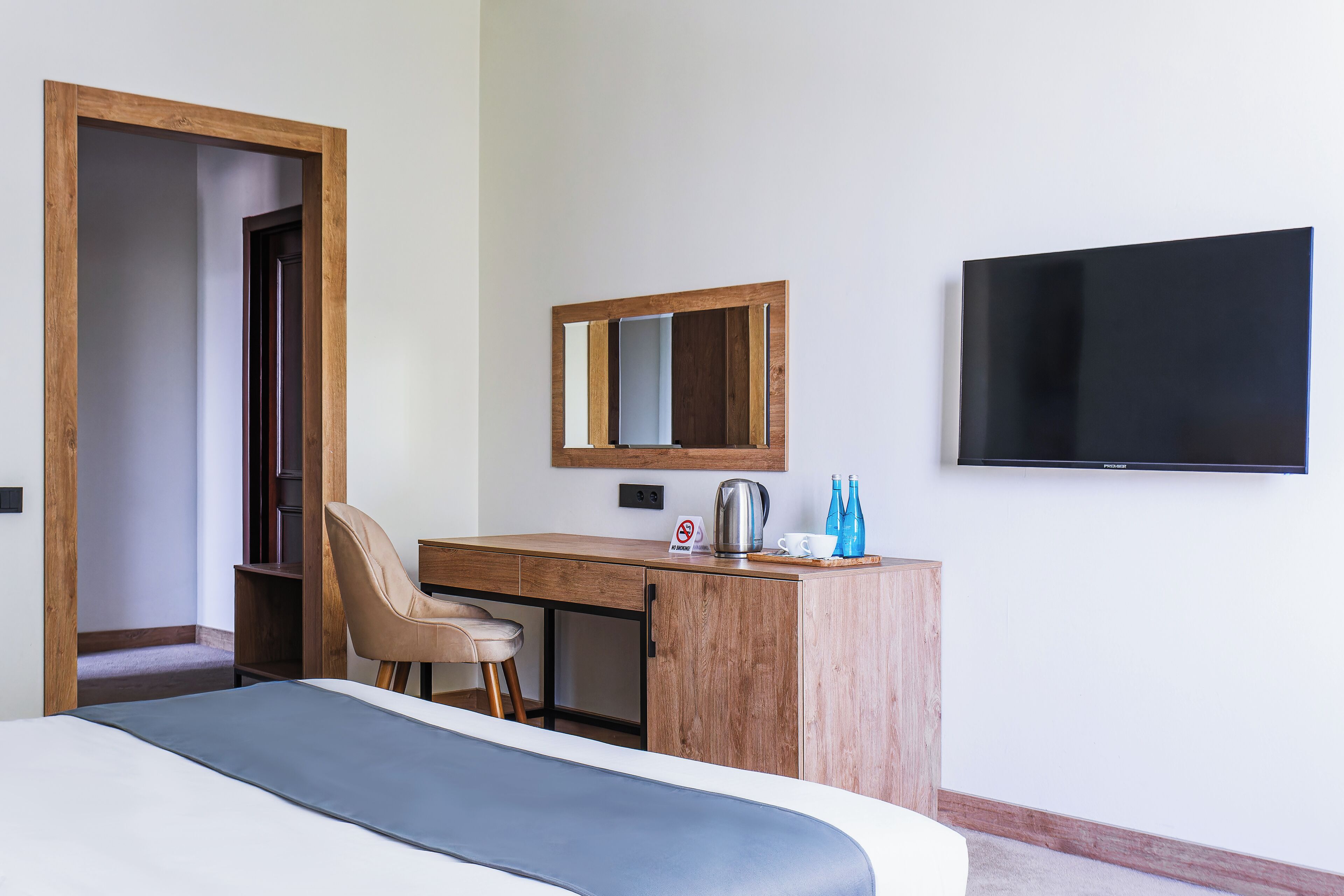 A hotel room with a bed, a desk, a chair, a television, and a coffee maker.