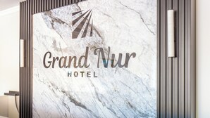 A marble wall with the text 'Grand Nur Hotel' and a logo. - Grand Nur (Tashkent)