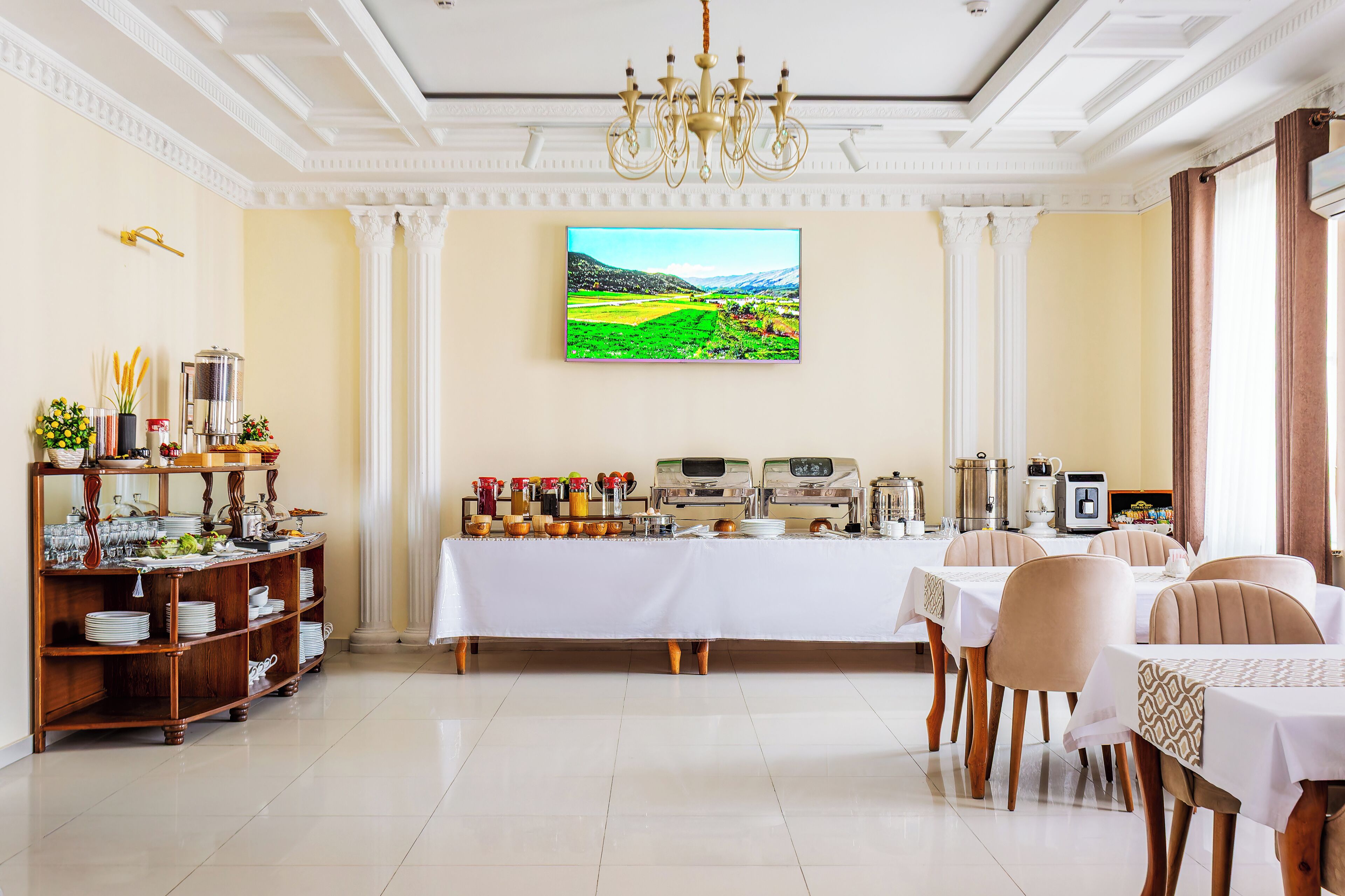 A dining area with a buffet setup, a chandelier, and a large window with a landscape view.