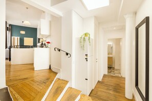 A modern interior with a staircase leading to a living area, a kitchen, and a dining space. - Family Suite - Louvre - Clery (Paris)