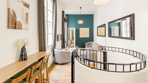Un salon moderne avec une balustrade noire incurvée, une table à manger en bois avec des chaises et un canapé.