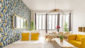 Een moderne hotelkamer met een groot bed, een zithoek met tafel en stoelen, en een helder raam met gordijnen.