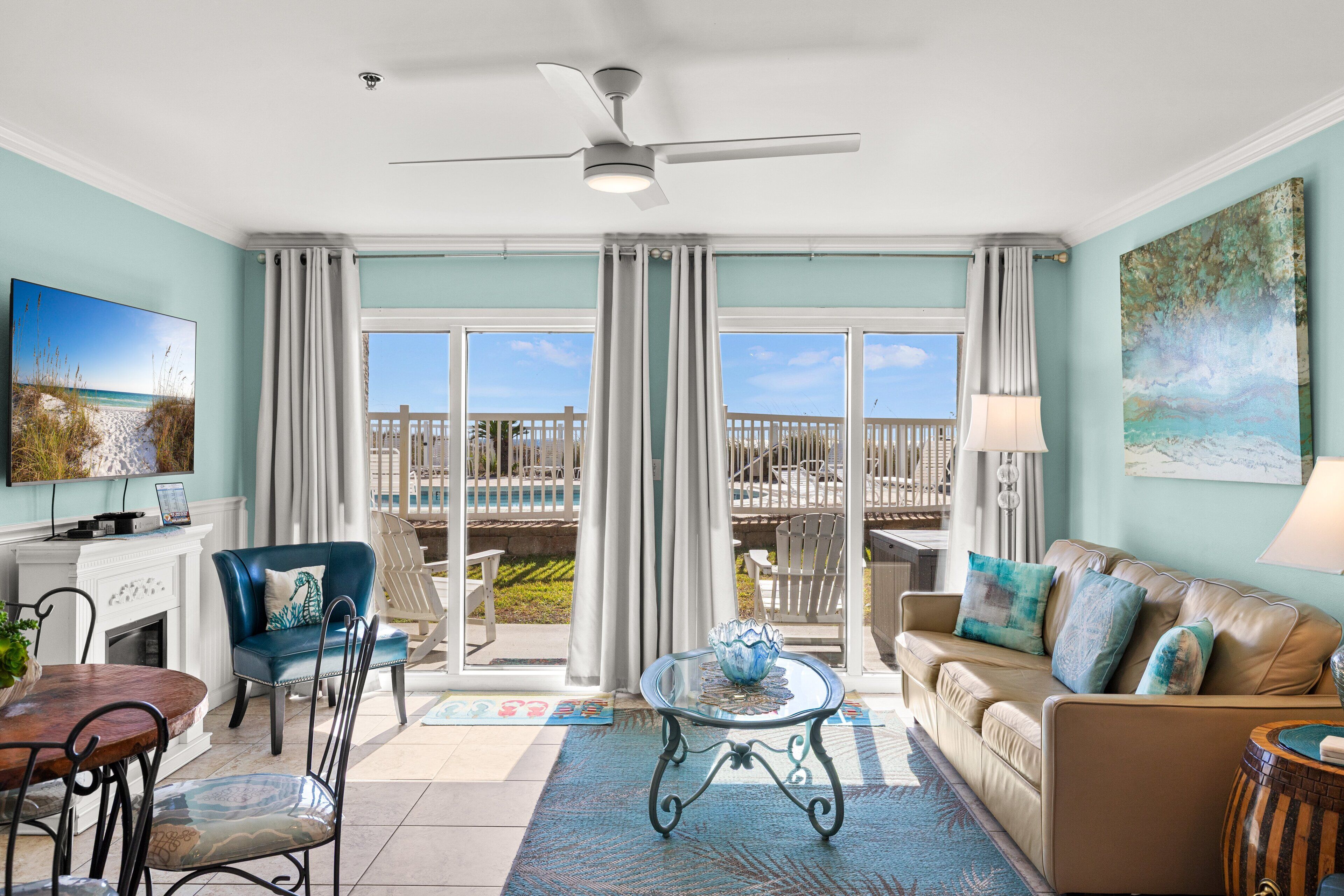 A spacious living room with a large window, a ceiling fan, a fireplace, and a dining area.