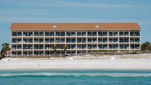 Un hôtel à plusieurs étages, doté d’un toit plat, situé sur une plage avec vue sur l’océan.