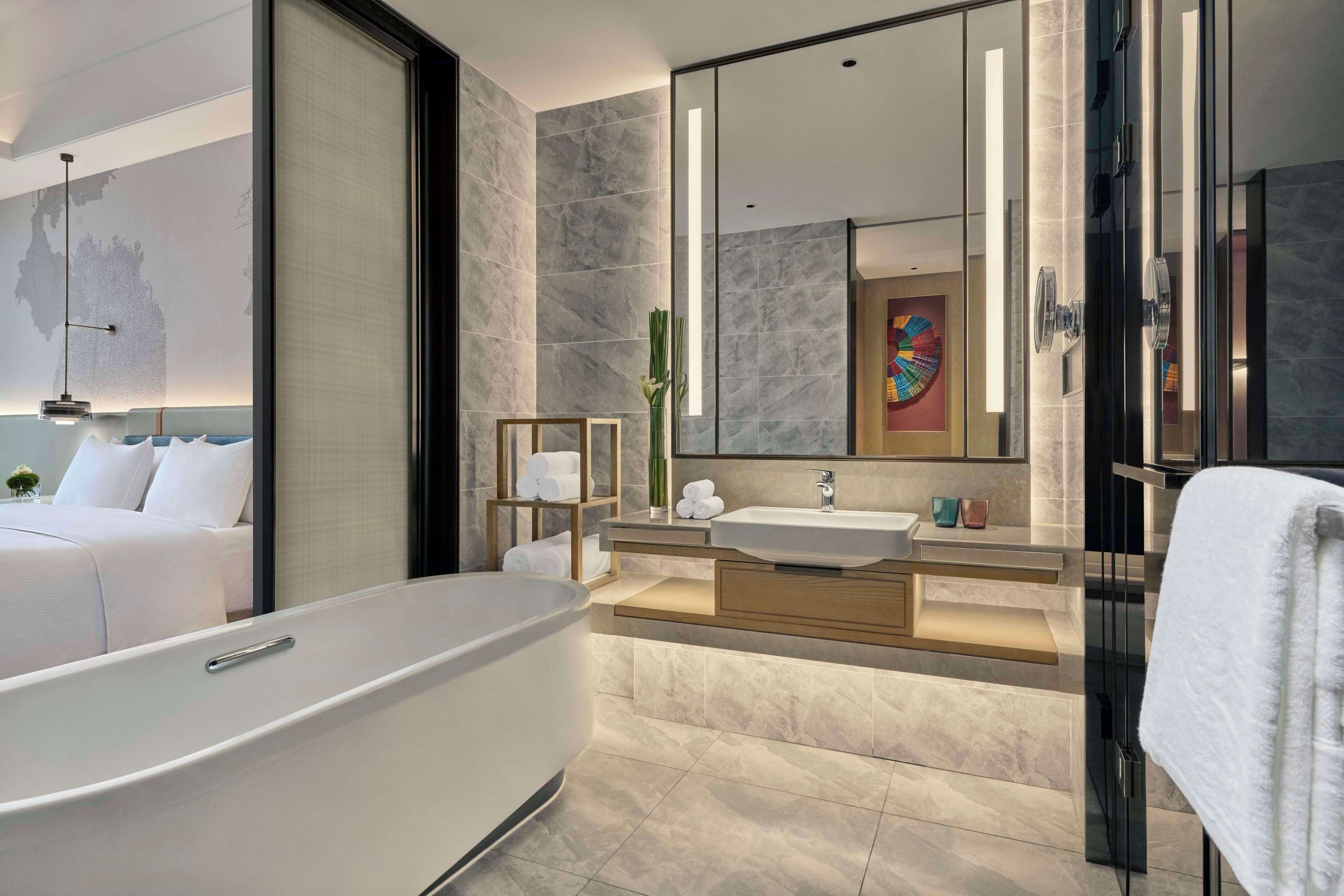 Une salle de bain moderne avec une baignoire sur pieds, un grand miroir et un meuble-lavabo doté d’un évier et d’un porte-serviettes.
