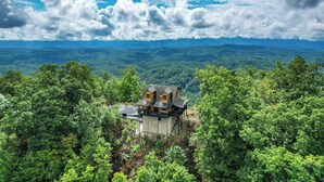 A house with a balcony, surrounded by dense forest, with a mountain range in the background. - Ridgetop VIEWS! Arcade+Hot Tub+Fire Pit+Privacy (Sevierville)