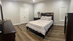 Un dormitorio con cama, mesitas de noche, cómoda y armario.
