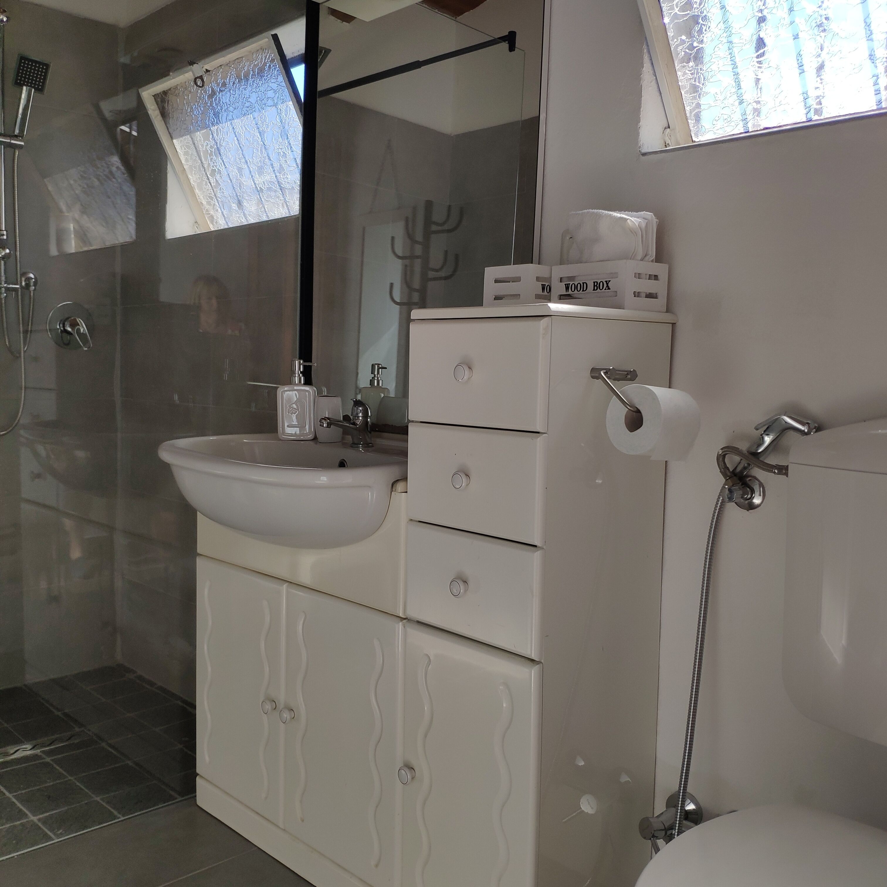 Une salle de bain avec un meuble-lavabo blanc, une cabine de douche en verre et des toilettes.