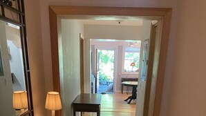 A hallway with a wooden floor, a table with lamps, and a mirror on the left.